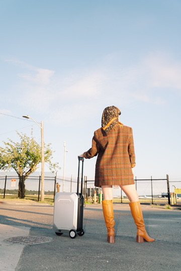 Erica from behind with a suitcase on an airport road