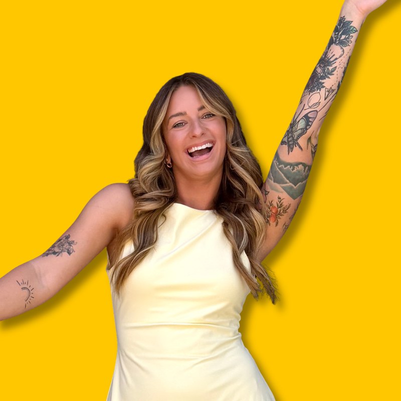 Portrait of Erica smiling with her arm raised against a yellow background